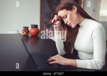 Junge überladene müde kaukasische Frau hat Hadache an Laptop in Heimbüro Stockfoto