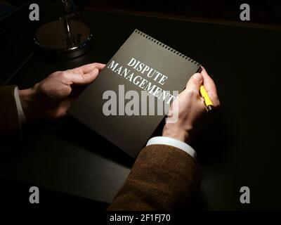 Mann hält Dispute Management Buch im dunklen Raum. Stockfoto