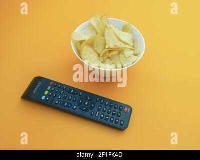 Filme ansehen Konzept mit Chips auf orangenen Hintergrund Foto Stockfoto