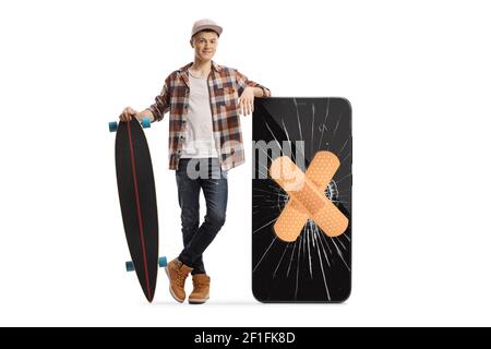 Ganzkörperportrait eines Skater-Typen mit Longboard Neben einem Telefon mit einem gesprungenen Bildschirm und posieren Verband isoliert auf weißem Hintergrund Stockfoto