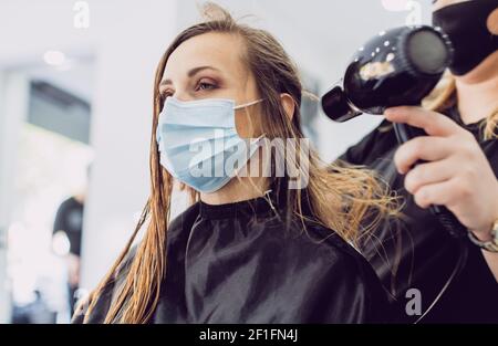 Friseur mit Fön und Kunde während Coronavirus Zeiten Stockfoto