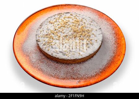 Haselnusskuchen mit Puderzucker und gehackten Haselnüssen in Orange Platte isoliert auf dem weißen Stockfoto