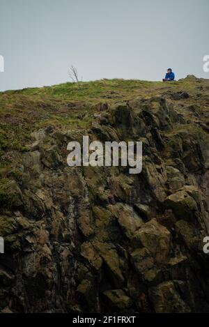 Edinburgh, Schottland, Großbritannien. März 2021, 8th. A Lone man enjoying a break at the top of Arthur's Seat, Edinburgh, 8 March 2021 Credit: Gayle McIntyre/Alamy Live News Stockfoto