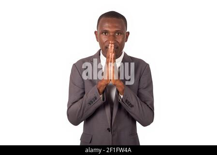 Junger Mann steht in Anzug auf weißem Hintergrund beten. Stockfoto