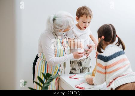 Bruder und Schwester besuchen ihre Großmutter und kochen zusammen in der Küche Stockfoto