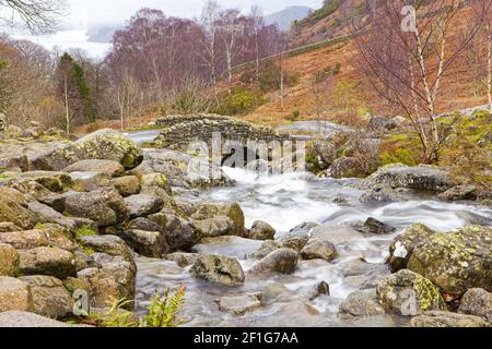 Ein feuchter Herbsttag im englischen Lake District - Barrow Beck fließt unter Ashness Bridge, Cumbria UK mit Derwentwater im Hintergrund Stockfoto