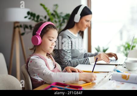 Mutter mit Schulmädchen zuhause, Fernunterricht und Home Office. Stockfoto