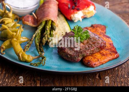 Gegrilltes Fleisch und grüner Spargel auf einem blauen Teller Stockfoto