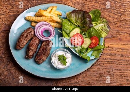 Cevapcici mit Pommes frites auf Holz Stockfoto