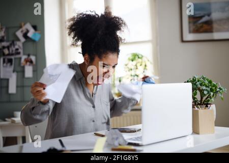 Frustrierte junge Frau mit Laptop drinnen zu Hause, Home-Office-Konzept. Stockfoto