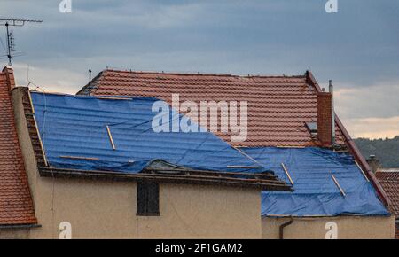 Die Schutzplane auf dem Dach beim Sturm mit Regen. Die Plane bedeckt das Dach des alten Hauses bei der Rekonstruktion. Stockfoto