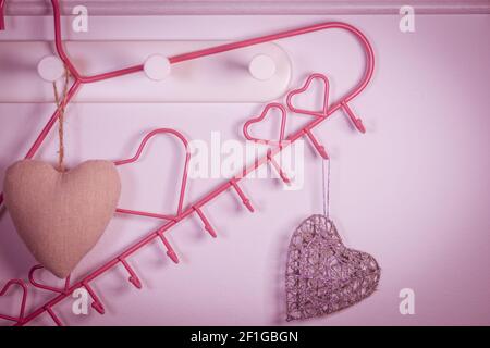 Rosa Herzen Kleiderbügel auf rotem Hintergrund. Valentines Tag Konzept Stockfoto