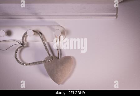 Herzförmiger Aufhänger auf rotem Hintergrund. Valentinstagskonzept Stockfoto