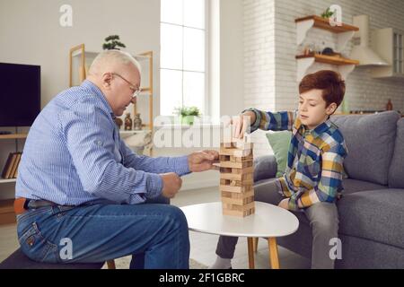 Ältere ältere ältere ältere ältere Mann Großvater sitzen und spielen Jenga-Brett Spiel mit seinem Enkel Stockfoto