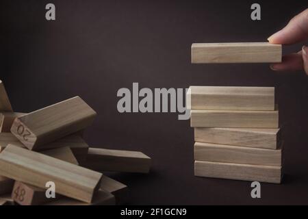 Hand bauen Holzblock im Turm, symbolisiert Bauerfolg. Unternehmensorganisation Startup-Konzept, Social Networking-Konzept. Stockfoto