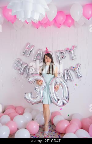 Frau steht in Dekorationen mit Ballons und Konfetti zum Geburtstag Party Stockfoto