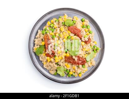 Quinoa-Haferbrei mit grüner Erbse, Mais und getrockneten Tomaten auf Keramikplatte isoliert auf weißem Hintergrund. Draufsicht, Nahaufnahme. Stockfoto