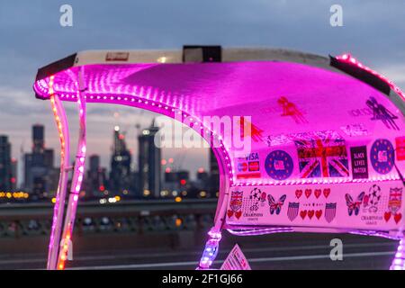 London, Großbritannien. März 2021, 08th. London, England am 8. März 2021. Eine Rikscha auf der Westminster Bridge leuchtet rosa Lichter, während die untergehende Sonne die Skyline der Stadt während einer andauernden dritten Coronavirus-Sperre bedeckt. Der Premierminister Boris Johnson hat einen Fahrplan zur Lockerung der Beschränkungen aufgestellt. (Foto von Dominika Zarzycka/Sipa USA) Quelle: SIPA USA/Alamy Live News Stockfoto