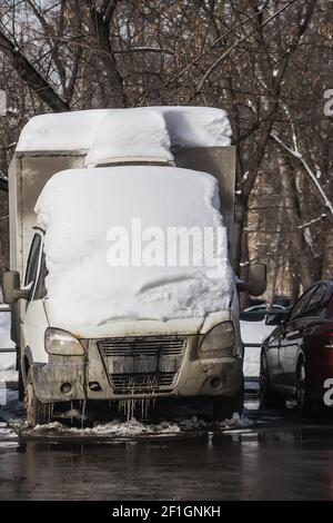 LKW unter dem Schnee auf dem Parkplatz in der Hof im Frühjahr Stockfoto