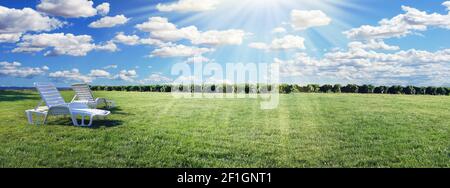 Gemütliche Sessel auf der linken Seite mit grünem Gras und Sonnenstrahlen im Garten der Hinterhof-Villa. Hotel und Reservierungen breiten Banner. Reise- und Entspannungskonzept. ICH Stockfoto