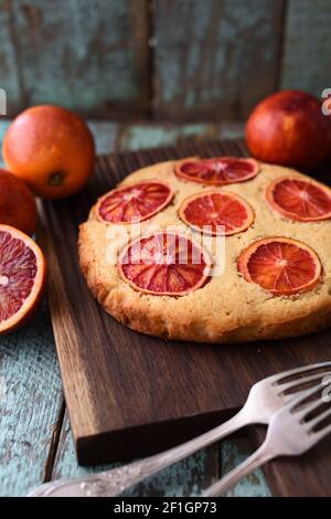 Hausgemachter leckerer Blutorangenkuchen auf dunklem Eichenbrett Schäbiger blauer Hintergrund vertikal Stockfoto