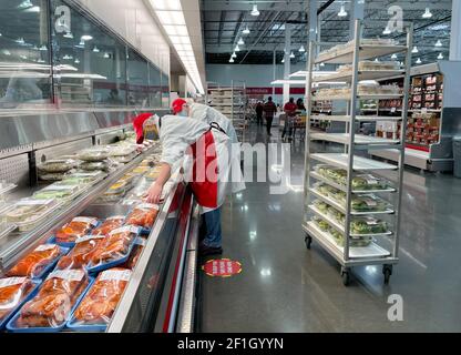 McKinney, TX USA - 22. Februar 2021: Mitarbeiter von Costco Deli stocken die Deli-Platten ins Regal Stockfoto