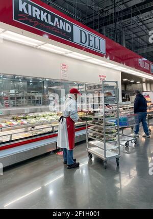 McKinney, TX USA - 22. Februar 2021: Mitarbeiter von Costco Deli stocken die Deli-Platten ins Regal Stockfoto