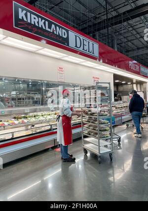 McKinney, TX USA - 22. Februar 2021: Mitarbeiter von Costco Deli stocken die Deli-Platten ins Regal Stockfoto