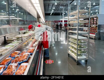 McKinney, TX USA - 22. Februar 2021: Mitarbeiter von Costco Deli stocken die Deli-Platten ins Regal Stockfoto