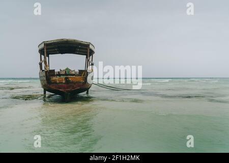 Flache Atoll-Sandbänke mit einsamem Fischerboot am Ebbe-Nungwi-Strand im Indischen Ozean auf der Insel Sansibar, Tansania. Exotische Länder tra Stockfoto