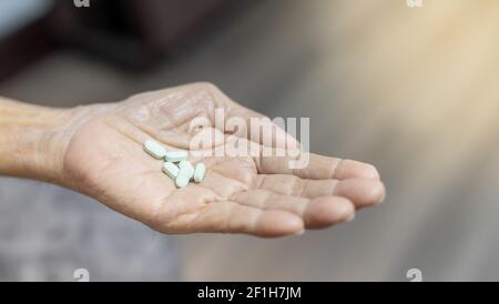 Der ältere Mann Hände Pille in seine Hand. Der Alte kümmert sich um die Gesundheit. Gesundheit und medizinisches Konzept. Stockfoto