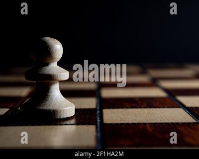 Ein Holzschach, das auf dem Schachbrett steht. Hoher Fotokontrast, Low-Key. Stockfoto