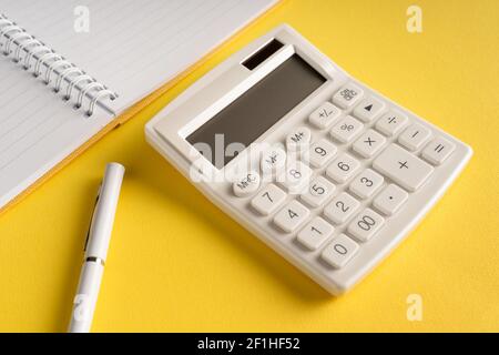 Büronotizbuch mit Bleistift und Taschenrechner auf einem Gelber Hintergrund Stockfoto