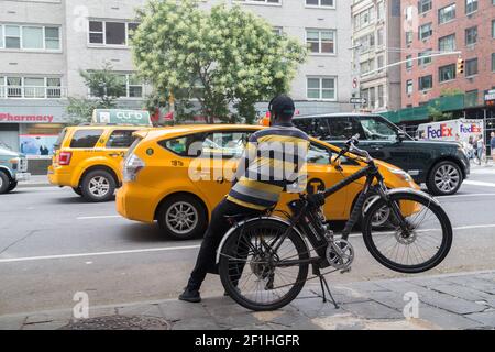 Lieferung Mann Schief Auf Seinem Fahrrad Beobachten Taxis Vorbei Auf Der Sixtth Avenue Stockfoto