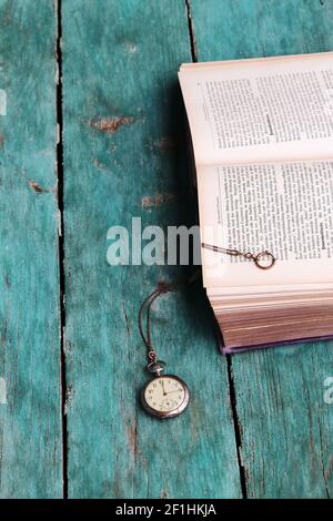 Eine antike Taschenuhr und ein altes Buch auf einem Blauer Holzfußboden Stockfoto