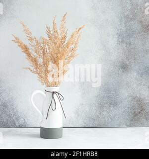 Pampas Gras in Keramikvase an der Wand. Stillleben Bouquet von getrockneten Blumen auf Stein Hintergrund mit Copy Space - Bild Stockfoto