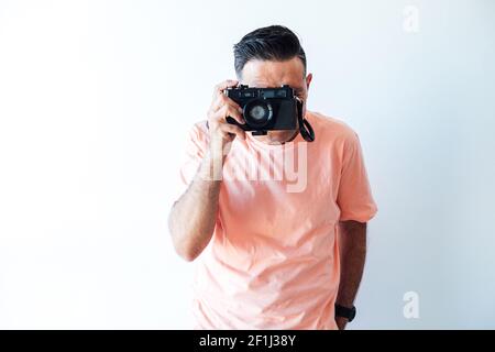 Mann in einem pinken T-Shirt, der ein Foto mit einer alten Fotomachine macht Stockfoto