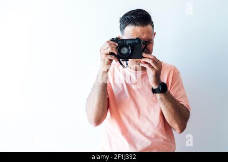 Mann in einem pinken T-Shirt, der ein Foto mit einer alten Fotomachine macht Stockfoto