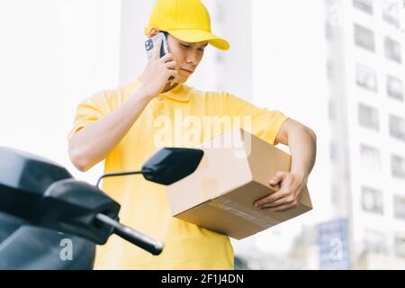 Der asiatische Spediteur ruft den Kunden an, um die Waren zu erhalten Stockfoto