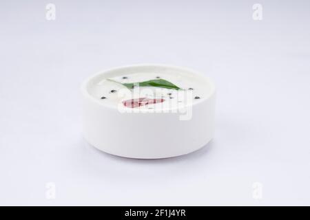 Coconut White Chutney, in einem weißen Tischgeschirr angeordnet und gewürzt mit Musterd, roter trockener Chili und Curryblättern. Stockfoto