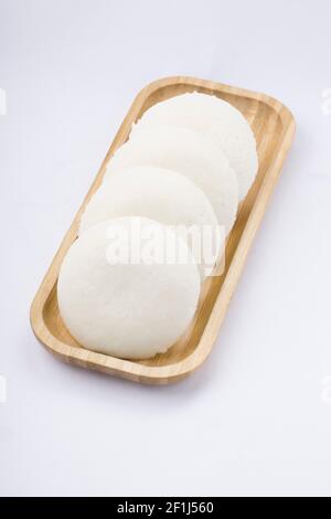 Idly oder Idli, südindisches Hauptfrühstück, das wunderschön in einer awooden Basis auf weißem Hintergrund angeordnet ist. Stockfoto