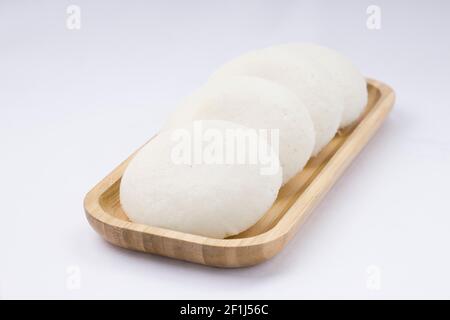 Idly oder Idli, südindisches Hauptfrühstück, das wunderschön in einer awooden Basis auf weißem Hintergrund angeordnet ist. Stockfoto