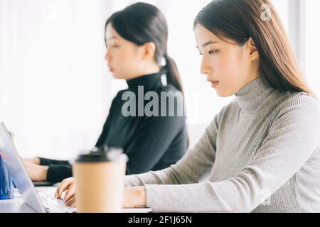 Zwei asiatische Geschäftsfrauen sind im Büro versammelt Stockfoto