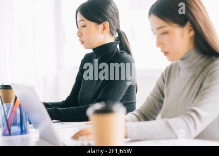 Zwei asiatische Geschäftsfrauen sind im Büro versammelt Stockfoto