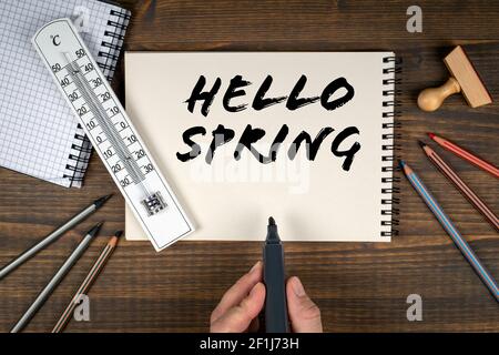 Hallo Frühling. Thermometer und Bürobedarf auf einem Holztisch. Stockfoto
