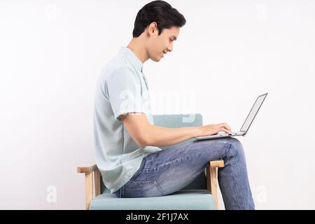 Ein hübscher Mann mit Laptop sitzt auf dem Sofa Stockfoto