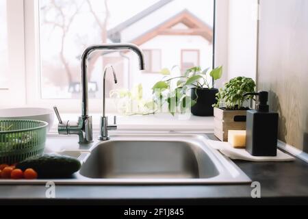 Grüne Salatblätter, Gurken und Tomaten in der Küche im Waschbecken bereit zum Waschen. Hochwertige Fotos Stockfoto