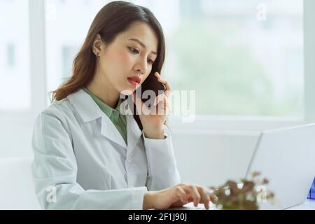 Schöne asiatische weibliche Arzt ist Anruf mit Patienten im Büro Stockfoto