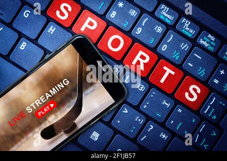Sport Live-Streaming-Konzept zeigt Eishockey-Spiel auf dem Smartphone mit Laptop High-Tech-Hintergrund ausgestrahlt. Zugriff auf digitale On-Demand-Inhalte i Stockfoto