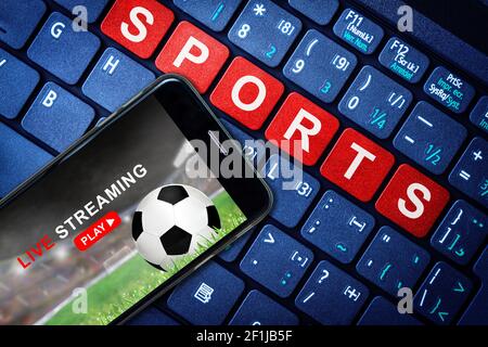 Sport Live-Streaming-Konzept zeigt Fußball oder Fußballspiel auf Smartphone mit Laptop High-Tech-Hintergrund. Zugänglich auf Abruf digital c Stockfoto